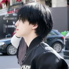 a man with black hair standing in the street