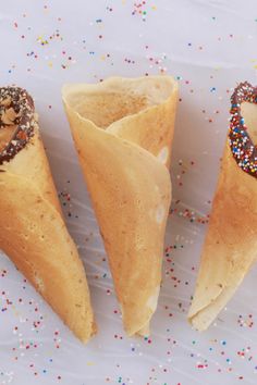 three ice cream cones with sprinkles and hearts on them sitting on a white surface