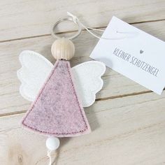 a pink and white angel keychain with a tag on it's side