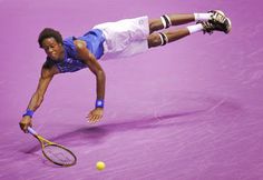 a tennis player dives to hit the ball with his racket during a match