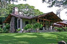 the house is surrounded by lush green trees and grass, with stone steps leading up to it