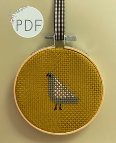 a cross stitch bird on a yellow background with a black and white checkered ribbon