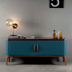 a blue chest with two drawers and a lamp next to it on a gray wall