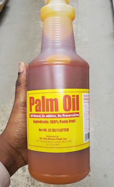 a hand holding a bottle of palm oil