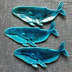 three blue whales sitting on top of a gray cloth covered table next to each other