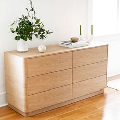 a wooden dresser sitting on top of a hard wood floor next to a white wall