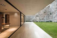 an empty room with wooden floors and large stone wall in the background, looking out onto a lush green lawn