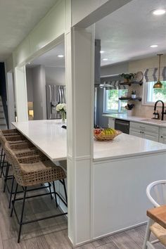 a kitchen with white counter tops and wooden chairs