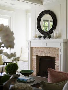 a living room filled with furniture and a fire place in front of a mirror on the wall