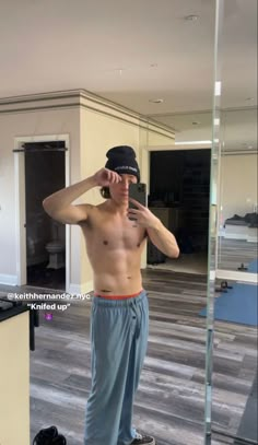 a shirtless man standing in front of a mirror with his hand on his head