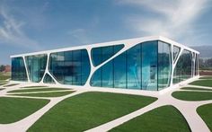 an unusual building with glass walls and grass