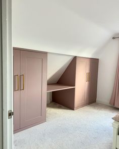 an attic bedroom with white carpet and pink cabinets