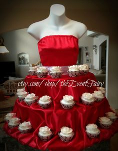 a dress made out of cupcakes sitting on top of a red table cloth