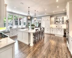 a large open kitchen with white cabinets and wood flooring is pictured in this image