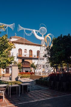 an outdoor dining area in front of a large white building with sculptures on the roof