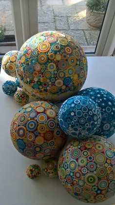 several colorful balls sitting on top of a table next to a window sill with a potted plant in the background