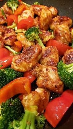 chicken and broccoli stir fry in a wok with red peppers, carrots and onions