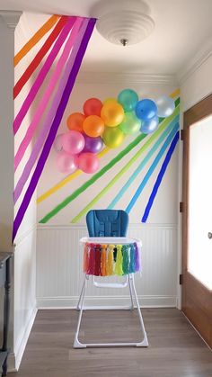 an empty room with balloons hanging from the ceiling and a chair in front of it