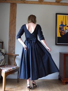 A beautiful black vintage dress, made in the 1980s by Laura Ashley. Made with a low cross-over style back, finished with a decorative bow. The skirt is very full, and the bodice is shaped with a  gentle V to the waist. Fastens with a hidden side zip. One hidden pocket in the skirt.  Made in Great Britain. 100% cotton. In very good vintage condition with no significant signs of age or wear. Marked as a UK 12 / EUR 38 / US 10, but may come up small. Chest: 33"/ 84cm Waist: 30"/ 78cm Length: 49"/ 1 Black Dress With Tie Back And Fitted Bodice, Black 1950s Style Wedding Dress, Black Dress With Fitted Bodice For Vintage Events, Vintage Evening Dresses With Bow, Black Dresses For Spring Vintage Events, Retro Black Dress With Fitted Bodice, Black Retro Dress With Fitted Bodice, Classic Black Dress For Vintage Events, Black Vintage Dress