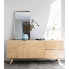 a wooden dresser with a mirror and vase on it in a white living room area