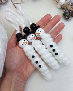 four snowman beads are held in the palm of someone's hand on a white surface