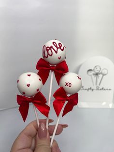 three lollipops with the word love on them are being held by a hand