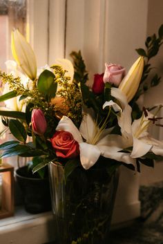 a vase filled with flowers sitting on top of a counter next to a window sill