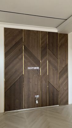 an empty room with wood paneling on the walls, and a shower head in the corner