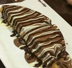 a piece of cake with chocolate and white icing on it sitting on a plate