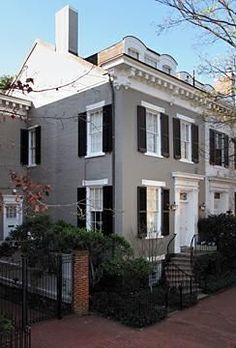 an apartment building with black shutters and white trim on the front, surrounded by trees