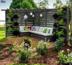 a couch sitting on top of a wooden bench in the middle of a garden area