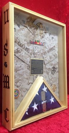 an american flag and medal display in a wooden frame on a red cloth covered surface