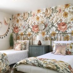 two beds in a bedroom with floral wallpaper