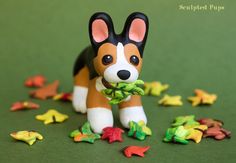 a small toy dog with leaves in it's mouth on a green surface surrounded by stars