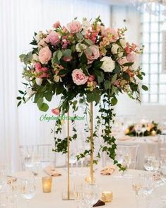 a tall centerpiece with pink and white flowers is on top of a round table