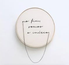 a handwritten quote on a white wall hanging from a hoop with black thread in it