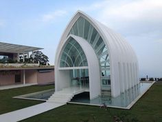 a large white building sitting on top of a lush green field