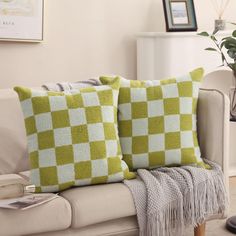 two green and white pillows sitting on top of a couch