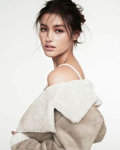 a woman in a fur coat posing for a magazine cover shoot with her hair pulled up into a bun