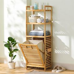 a wooden shelf with towels and other items on it next to a potted plant