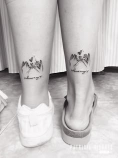 black and white photo of two legs with small tattoos on their ankles, one is holding the other's leg