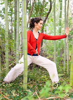 a woman is doing yoga in the middle of some bamboo trees with her arms stretched out