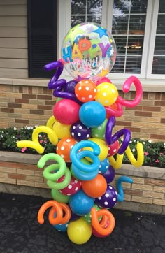 a bunch of balloons are stacked on top of each other in front of a house