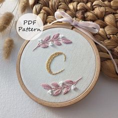 the embroidery pattern is being displayed in front of a basket with flowers and leaves on it