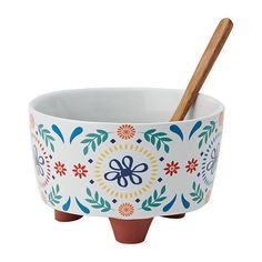 a ceramic bowl with a wooden spoon in the center and colorful flowers on it, set against a white background