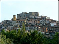 an old city with lots of buildings on top of it's sides and trees in the foreground