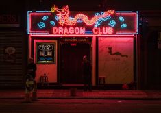 a neon dragon club sign lit up at night