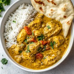 a white bowl filled with chicken and rice next to a pita bread on top of a table