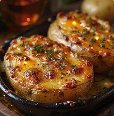 two baked potatoes with cheese and herbs in a cast iron skillet