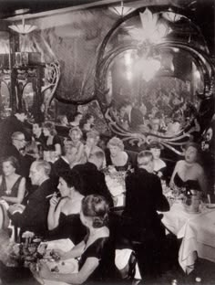 an old black and white photo of people sitting at tables